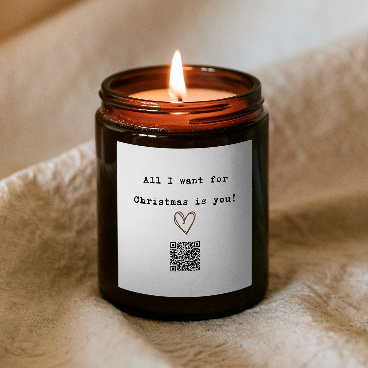 Égő Kiskedves „Dallamos” karácsonyi gyertya, a címkén rajzolt szív, QR-kód és az All I want for Christmas is you felirat
