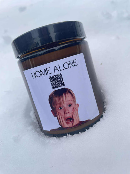 Kiskedves „Dallamos” karácsonyi gyertya a hóban, a címkén QR-kód és a Home Alone felirat